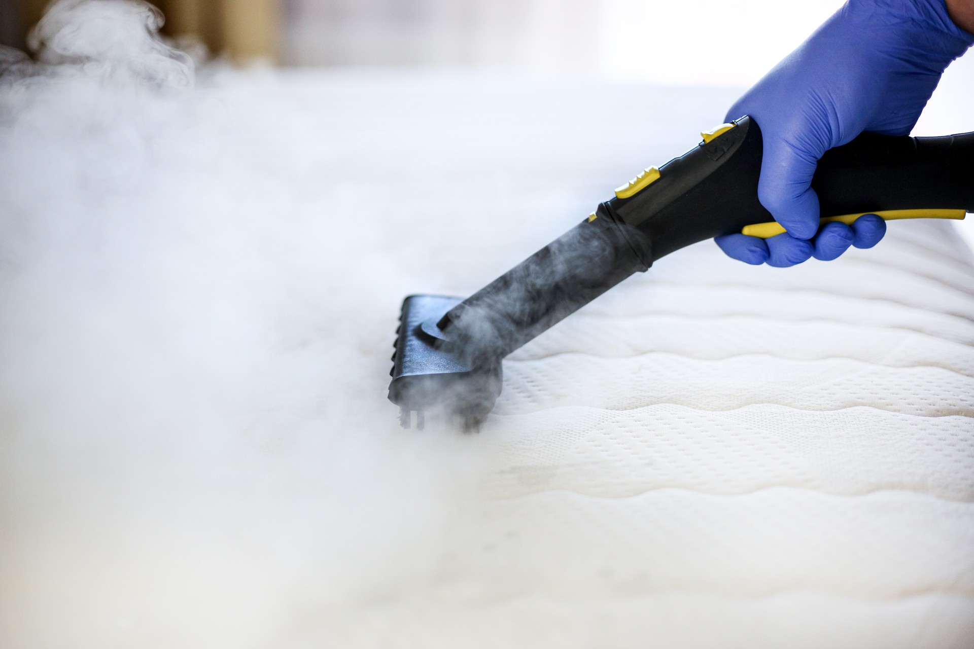 Cleaning and disinfection of the mattress in the bedroom with hot steam. Professional cleaning process